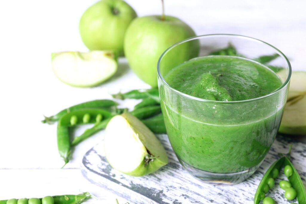 Glas groene smoothie tussen groene appels