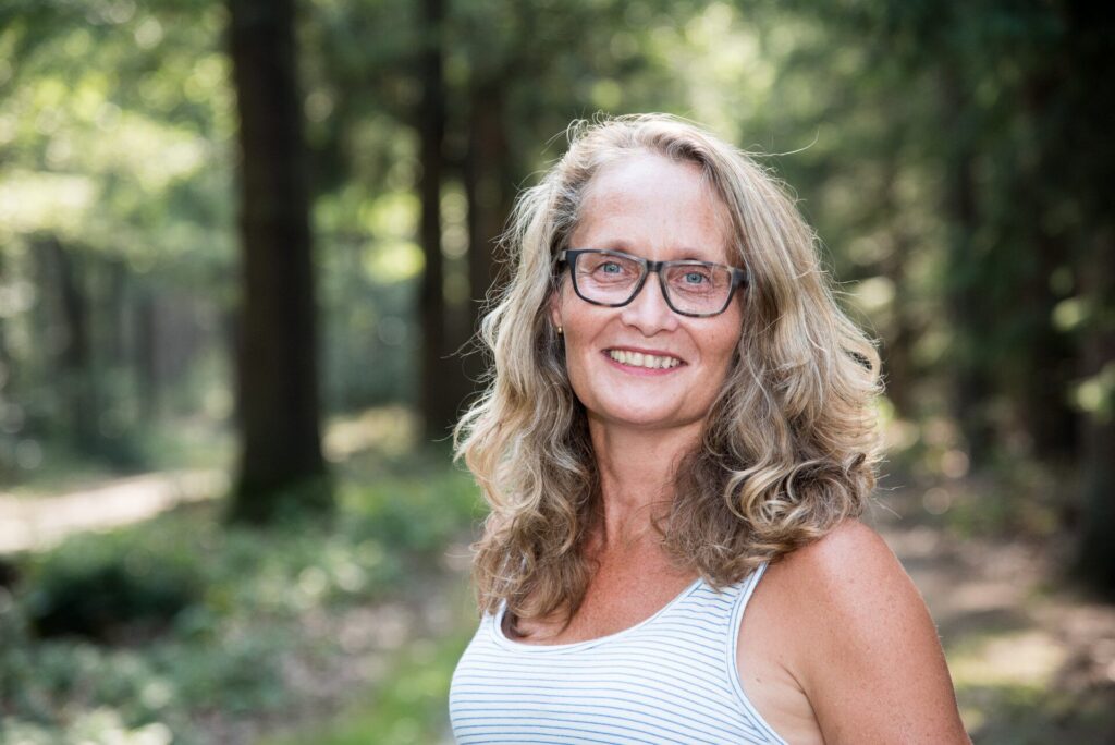 Marita Swart lacht in de camera, buiten tussen de bomen