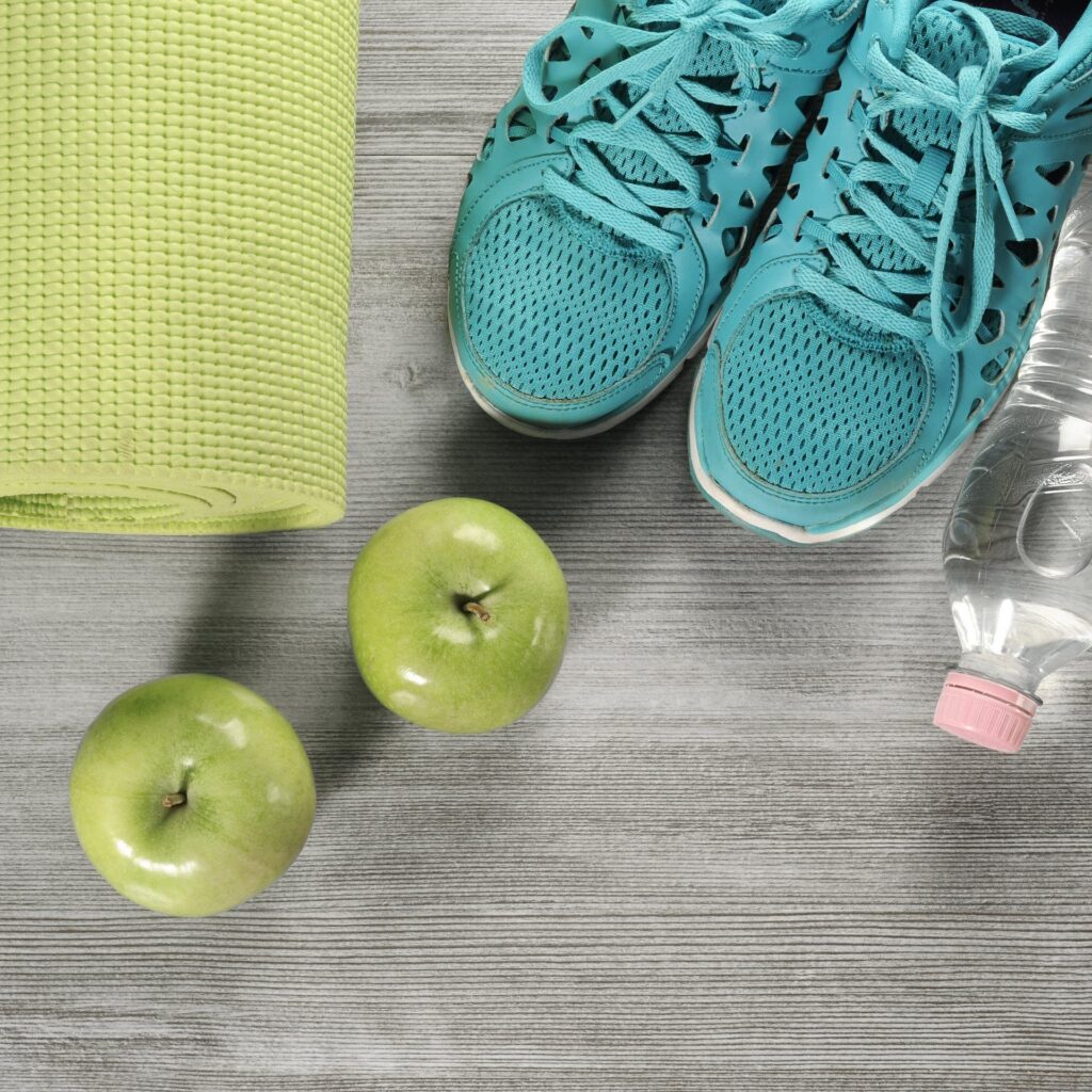 Sportschoenen, een yogamat en groene appels